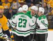 Dallas Stars defenseman Miro Heiskanen celebrates his goal in a huddle with teammates as a Nashville Predators player skates by.
