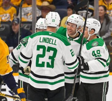 Dallas Stars defenseman Miro Heiskanen celebrates his goal in a huddle with teammates as a Nashville Predators player skates by.