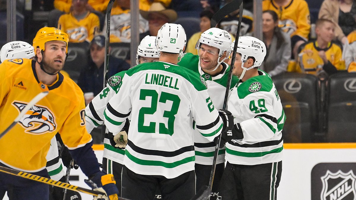 Dallas Stars defenseman Miro Heiskanen celebrates his goal in a huddle with teammates as a Nashville Predators player skates by.