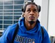 Dallas Mavericks rookie forward Morez Johnson Jr. climbs the stairs to the team plane wearing a blue Dallas hoodie and headphones.