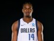 Mavericks rookie forward Morez Johnson Jr. stands facing the camera in a white Dallas No. 14 jersey against a black backdrop.