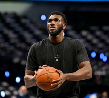 Dallas Mavericks center Moussa Cissé holds a basketball at his chest during pregame warmups in a black team T-shirt.