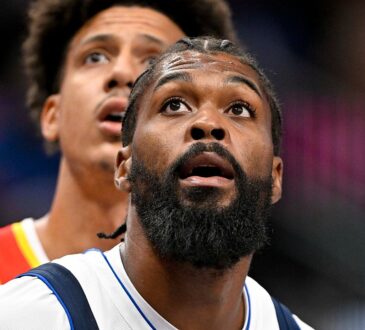 Mavericks forward Naji Marshall looks up as a Hawks player watches behind him.