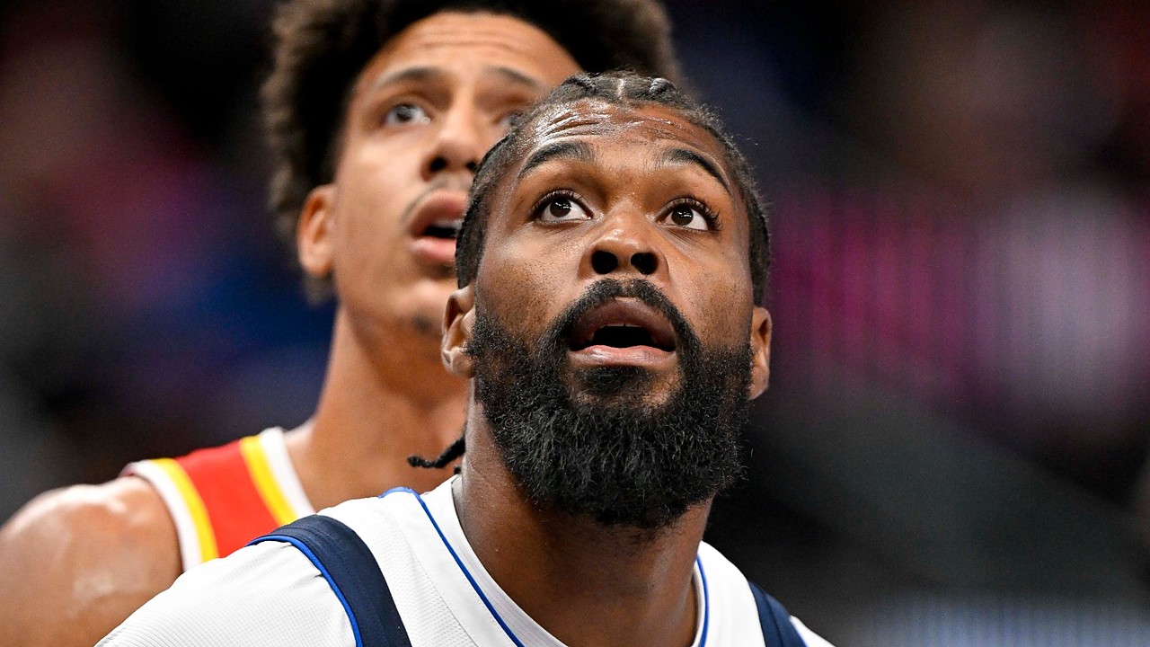 Mavericks forward Naji Marshall looks up as a Hawks player watches behind him.