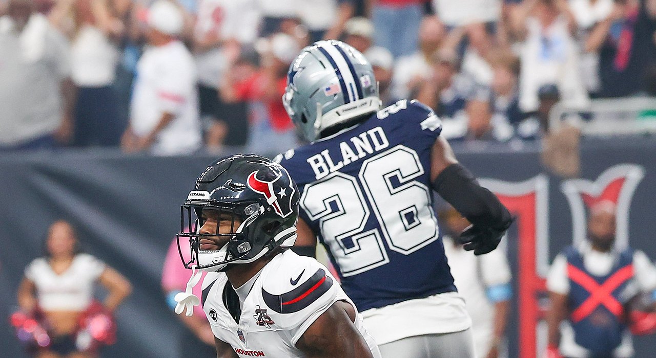 Texans wide receiver Nico Collins kneels in the end zone with the ball as Cowboys cornerback DaRon Bland turns away.