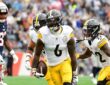 Steelers linebacker Patrick Queen carries the ball after an interception as teammates rush to celebrate.