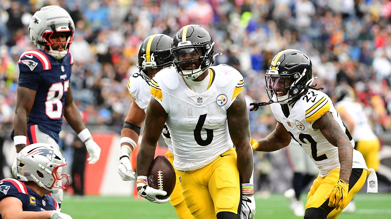 Steelers linebacker Patrick Queen carries the ball after an interception as teammates rush to celebrate.