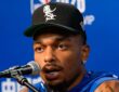 Mavericks forward P.J. Washington speaks into a microphone in front of an NBA China Games backdrop.