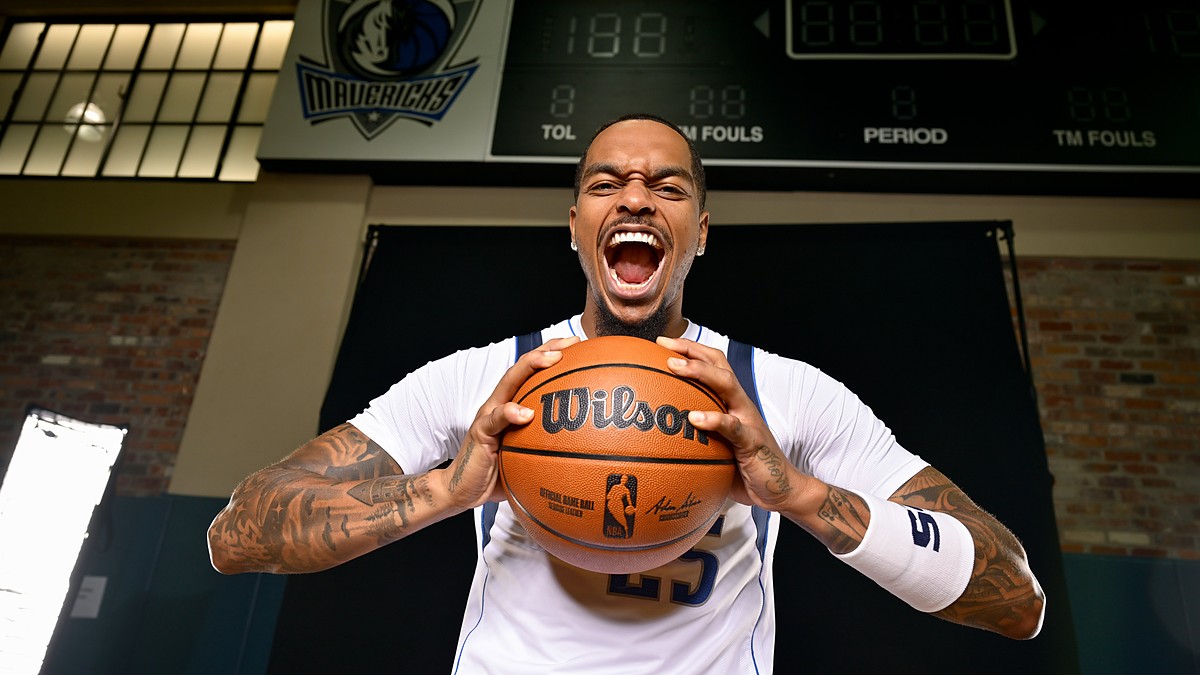 Dallas Mavericks forward P.J. Washington yells while gripping a basketball beneath a Mavericks logo and scoreboard.