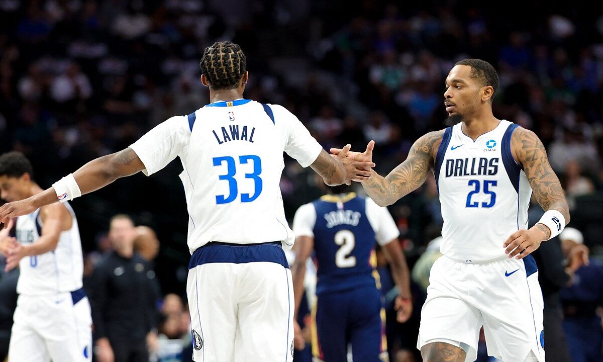 Dallas Mavericks forward P.J. Washington slaps hands with forward Tobi Lawal, who has his back to the camera.