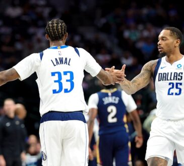 Dallas Mavericks forward P.J. Washington slaps hands with forward Tobi Lawal, who has his back to the camera.