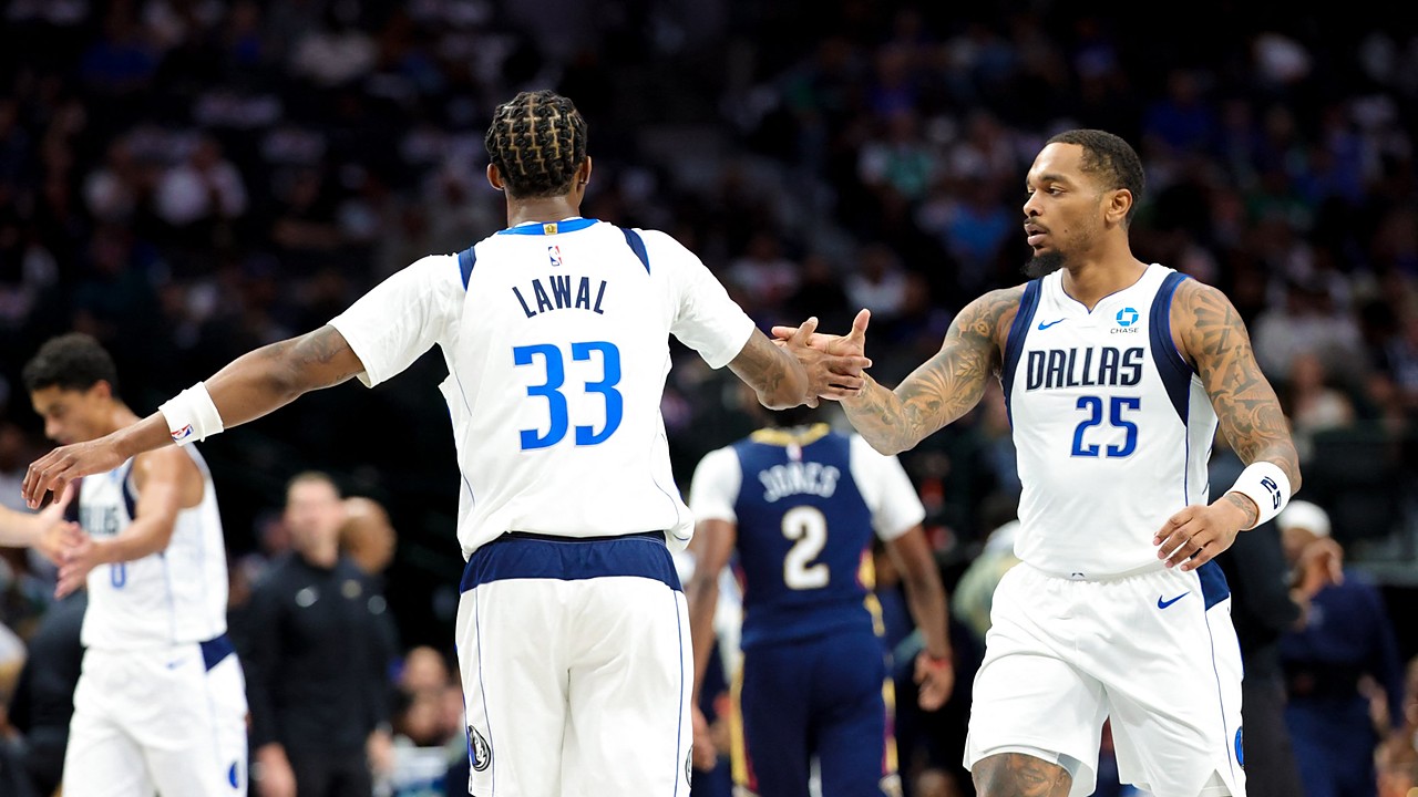 Dallas Mavericks forward P.J. Washington slaps hands with forward Tobi Lawal, who has his back to the camera.