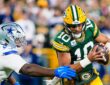 Green Bay Packers quarterback Jordan Love tucks the ball and runs as Dallas Cowboys defensive lineman Quinnen Williams reaches for him.