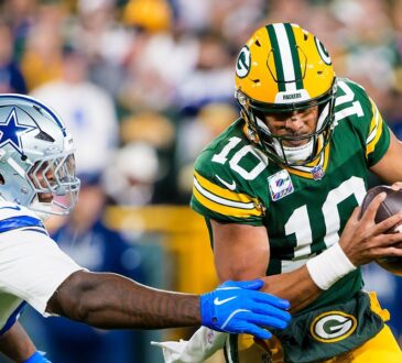 Green Bay Packers quarterback Jordan Love tucks the ball and runs as Dallas Cowboys defensive lineman Quinnen Williams reaches for him.