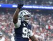 Cowboys defensive tackle Quinnen Williams raises his right fist in celebration in front of a packed crowd.