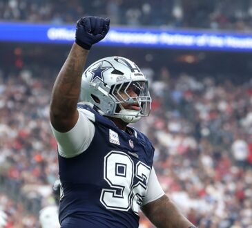 Cowboys defensive tackle Quinnen Williams raises his right fist in celebration in front of a packed crowd.