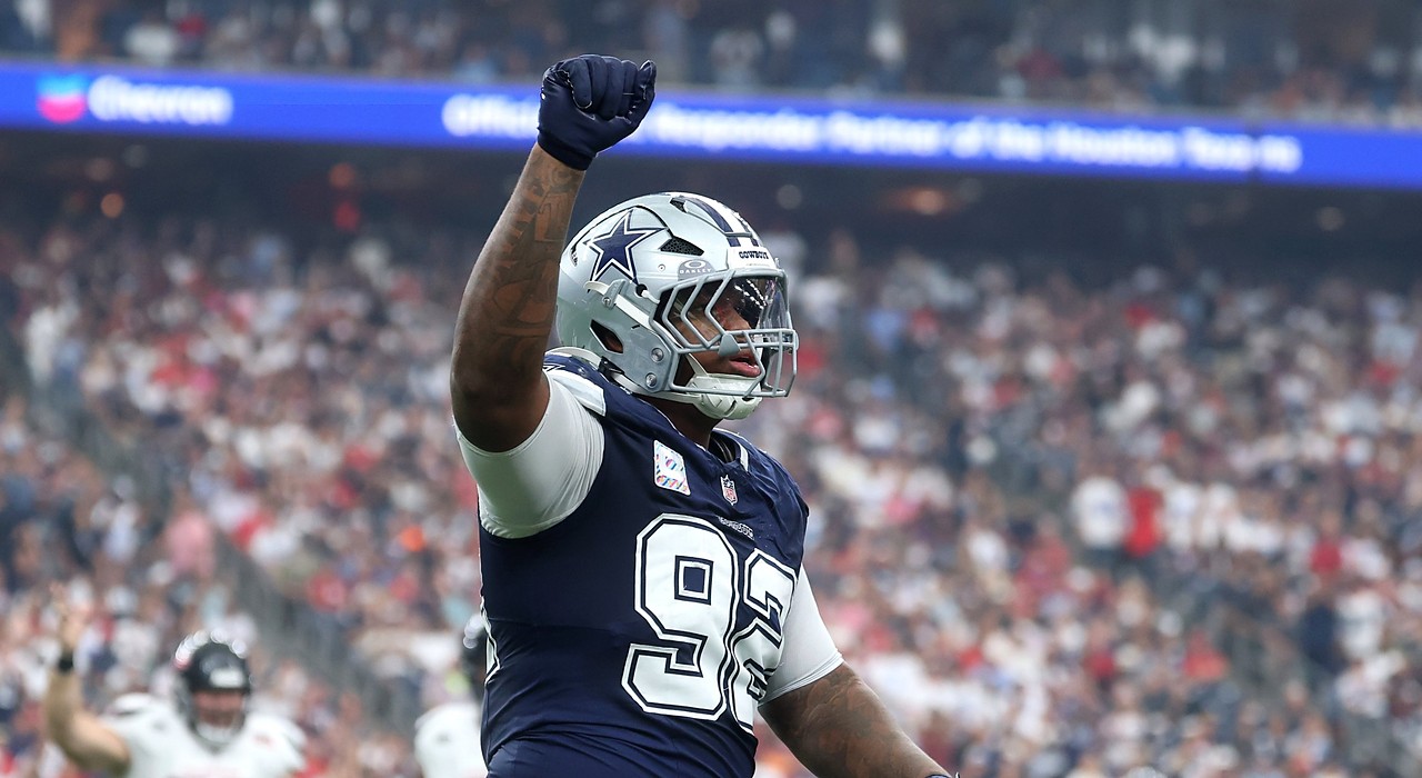 Cowboys defensive tackle Quinnen Williams raises his right fist in celebration in front of a packed crowd.