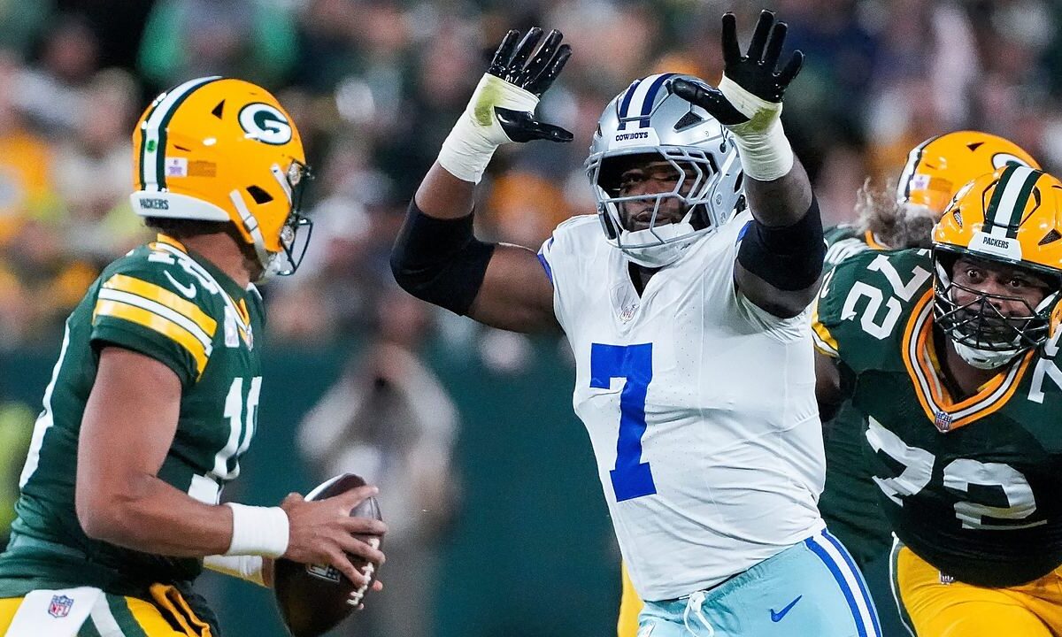 Dallas Cowboys linebacker Rashan Gary rushes with both arms raised toward Green Bay Packers quarterback Jordan Love.