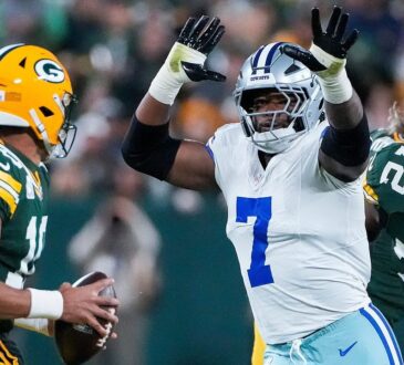 Dallas Cowboys linebacker Rashan Gary rushes with both arms raised toward Green Bay Packers quarterback Jordan Love.