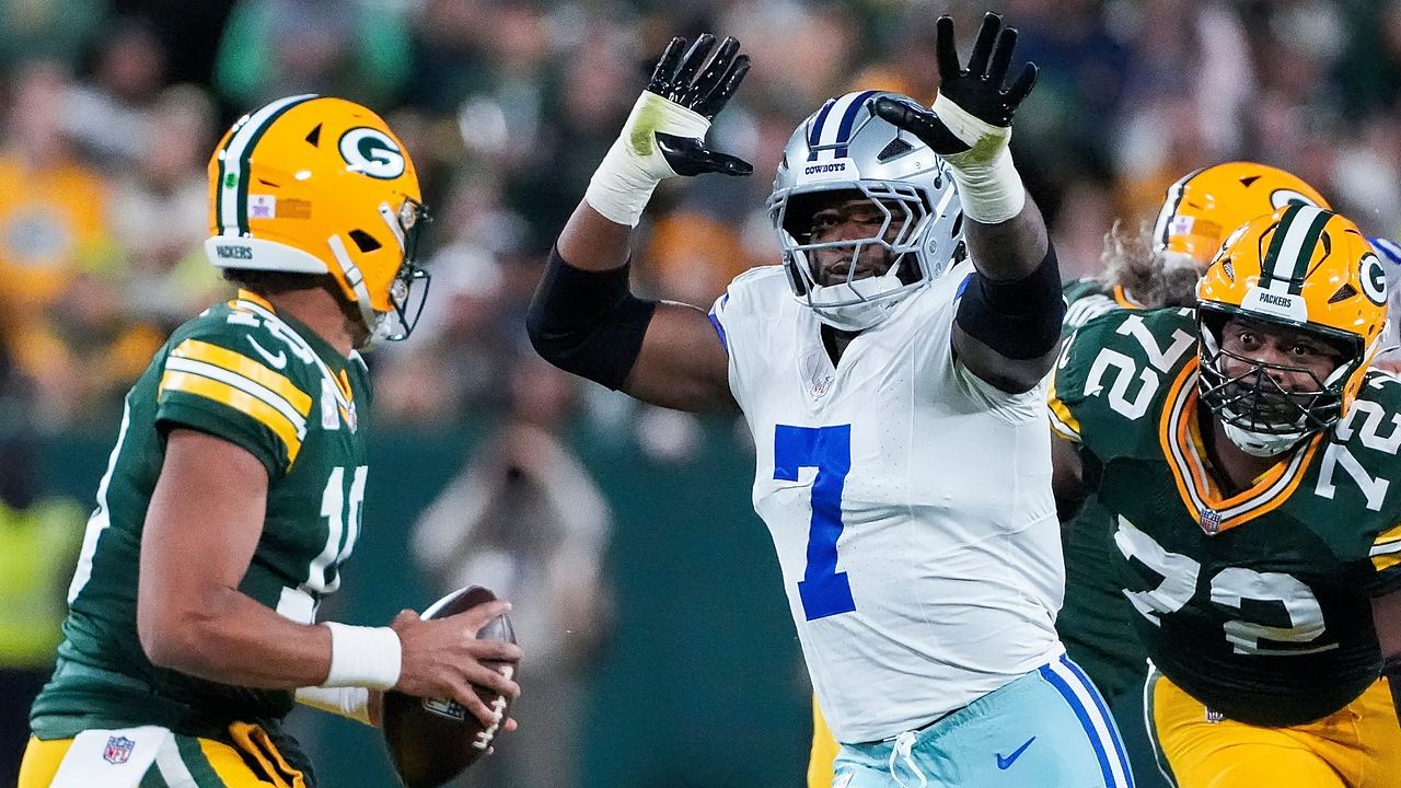 Dallas Cowboys linebacker Rashan Gary rushes with both arms raised toward Green Bay Packers quarterback Jordan Love.