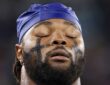 Dallas Cowboys linebacker Rashan Gary closes his eyes in a tight close-up, wearing eye black and a blue skull cap.