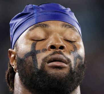 Dallas Cowboys linebacker Rashan Gary closes his eyes in a tight close-up, wearing eye black and a blue skull cap.