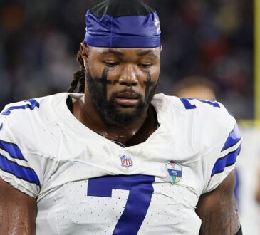Dallas Cowboys linebacker Rashan Gary looks down on the field wearing a team skull cap and eye black.