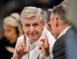 Dallas Mavericks CEO Rick Welts smiles and raises one finger as Dallas Wings CEO Greg Bibb, facing him, does the same.
