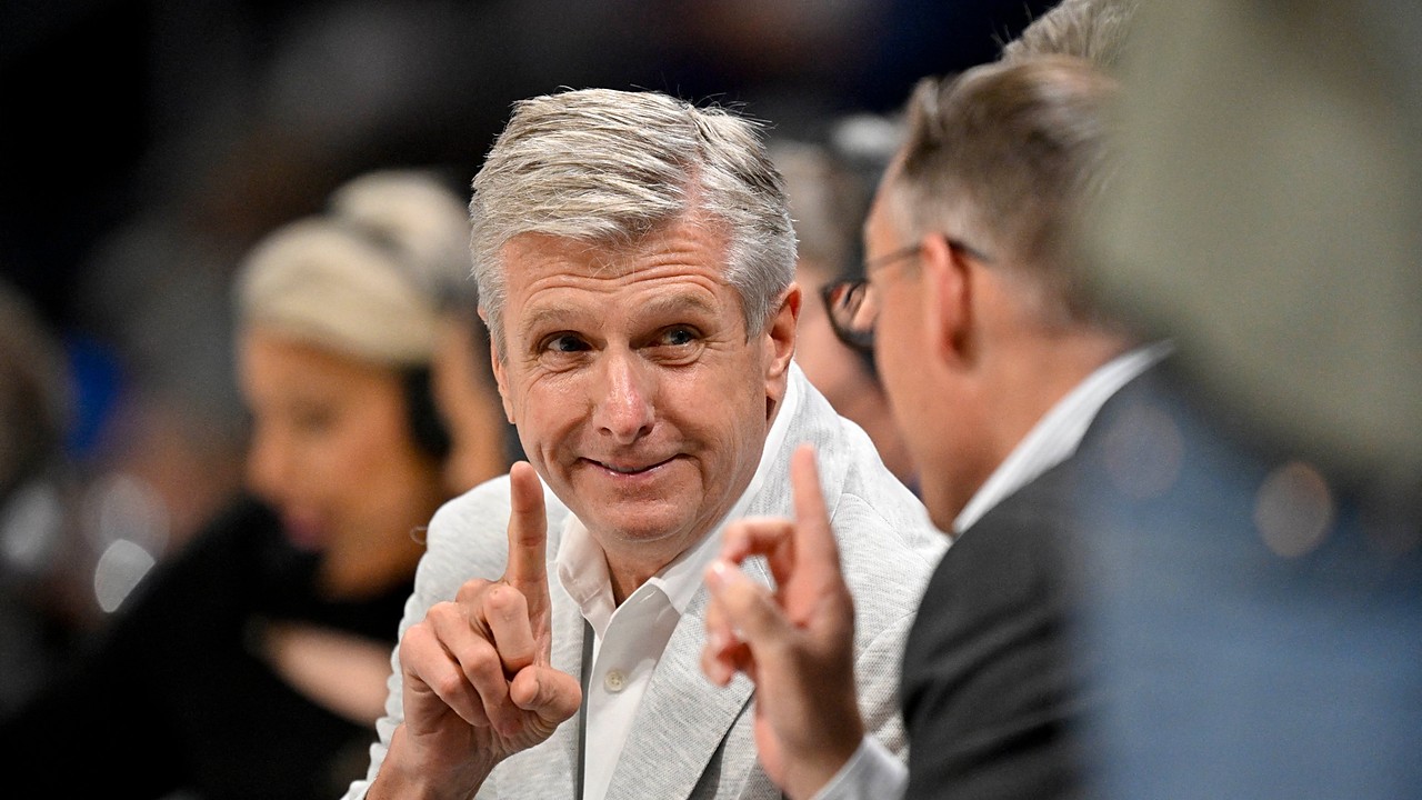 Dallas Mavericks CEO Rick Welts smiles and raises one finger as Dallas Wings CEO Greg Bibb, facing him, does the same.