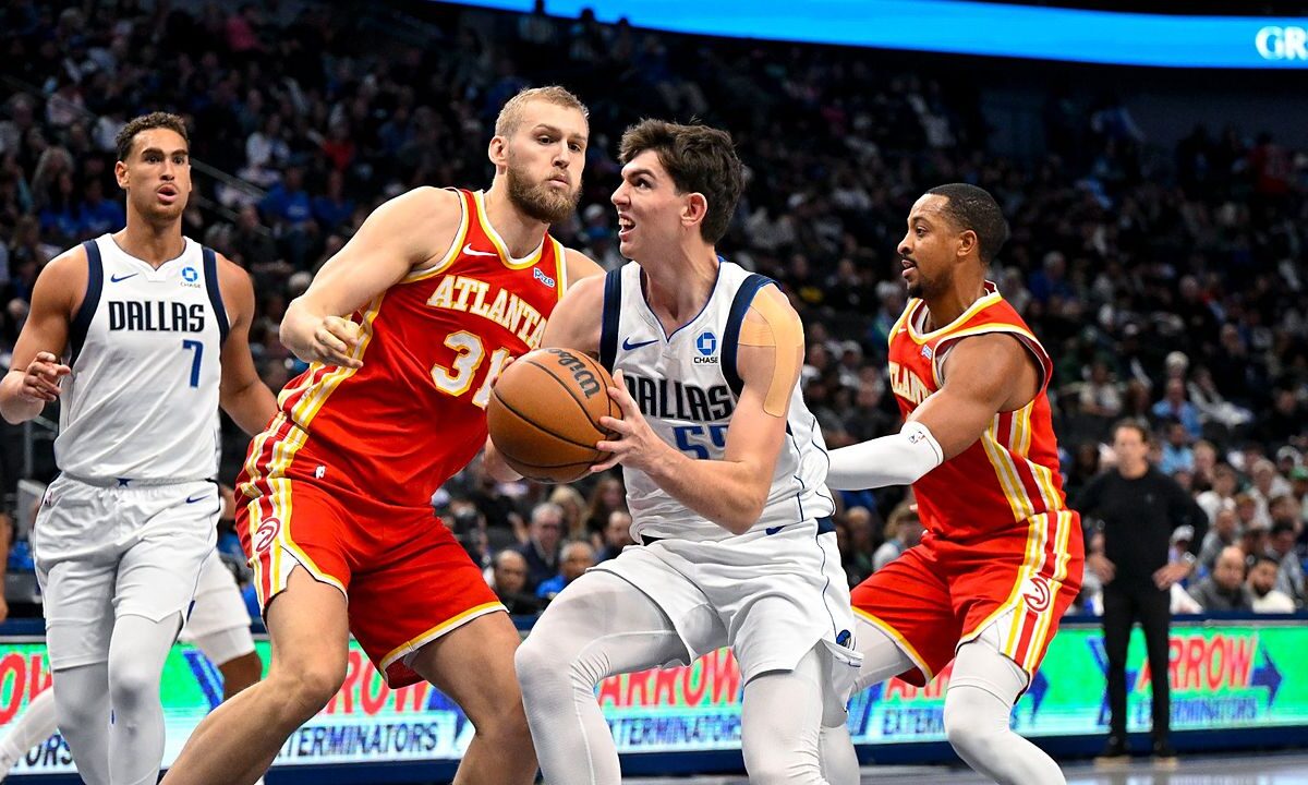 Dallas Mavericks forward Sergio de Larrea drives with the ball between Atlanta Hawks defenders as a teammate trails the play.
