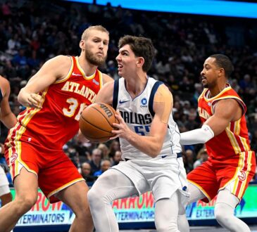 Dallas Mavericks forward Sergio de Larrea drives with the ball between Atlanta Hawks defenders as a teammate trails the play.