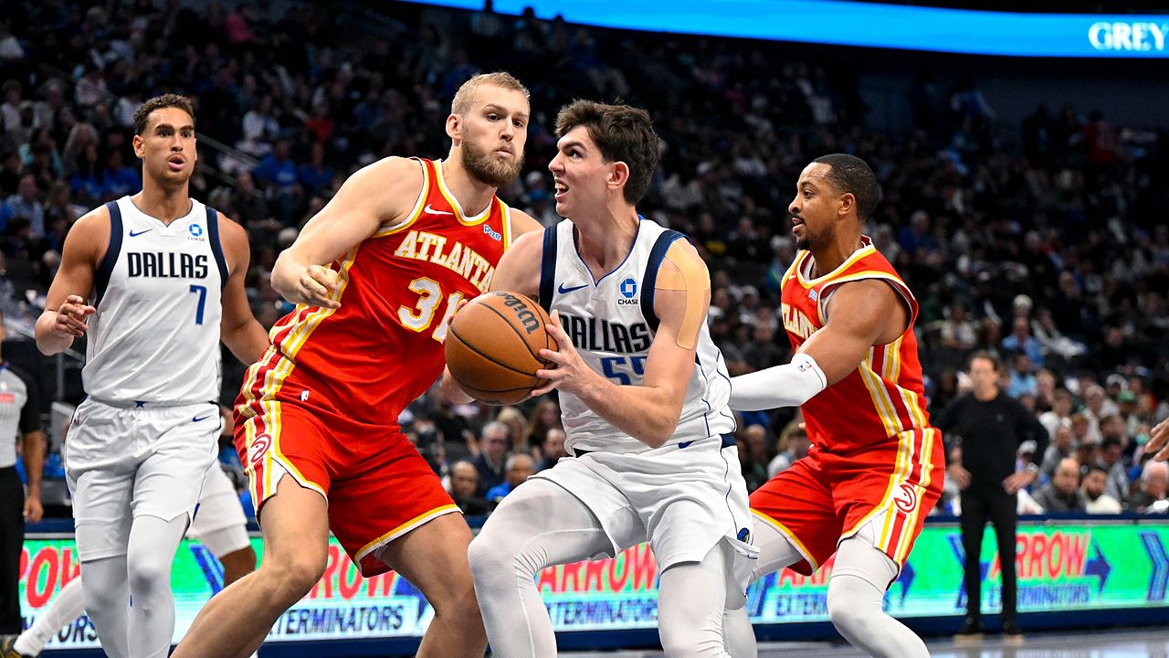 Dallas Mavericks forward Sergio de Larrea drives with the ball between Atlanta Hawks defenders as a teammate trails the play.