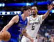 Dallas Mavericks guard Sergio de Larrea drives with the ball as San Antonio Spurs guard Stephon Castle defends with an arm raised.