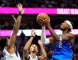 Oklahoma City Thunder guard Shai Gilgeous-Alexander rises for a shot as two Dallas Mavericks defenders reach up to contest.
