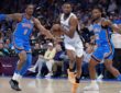 San Antonio Spurs guard De'Aaron Fox #4 drives between Oklahoma City Thunder defenders Jalen Williams #8 and Cason Wallace #22 at Paycom Center.