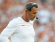 Texas head coach Steve Sarkisian looks down with a hand on his hip while wearing a headset on the sideline.