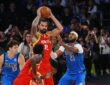 Houston Rockets center Steven Adams holds the ball overhead as Dallas Mavericks center Daniel Gafford defends him.