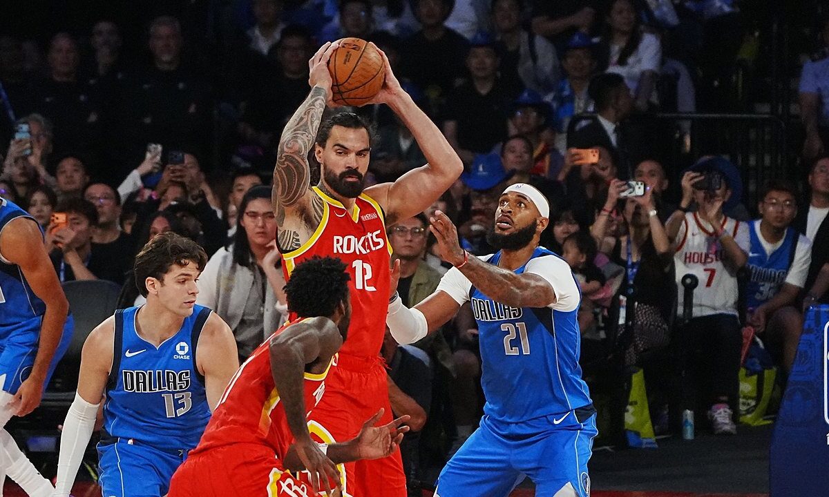 Houston Rockets center Steven Adams holds the ball overhead as Dallas Mavericks center Daniel Gafford defends him.