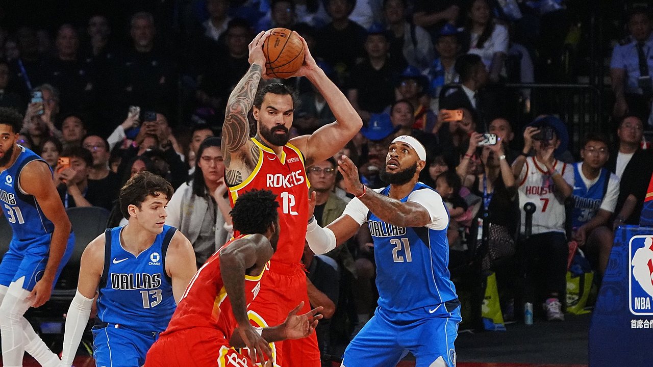Houston Rockets center Steven Adams holds the ball overhead as Dallas Mavericks center Daniel Gafford defends him.