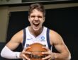 Dallas Mavericks forward Tarik Biberović yells while gripping a basketball with both hands in a white Dallas jersey.
