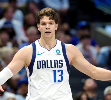Mavericks forward Tarik Biberović gestures with both arms out during a game.