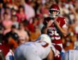 Oklahoma place kicker Tate Sandell adjusts his shoulder pads while lining up a field goal behind the line.