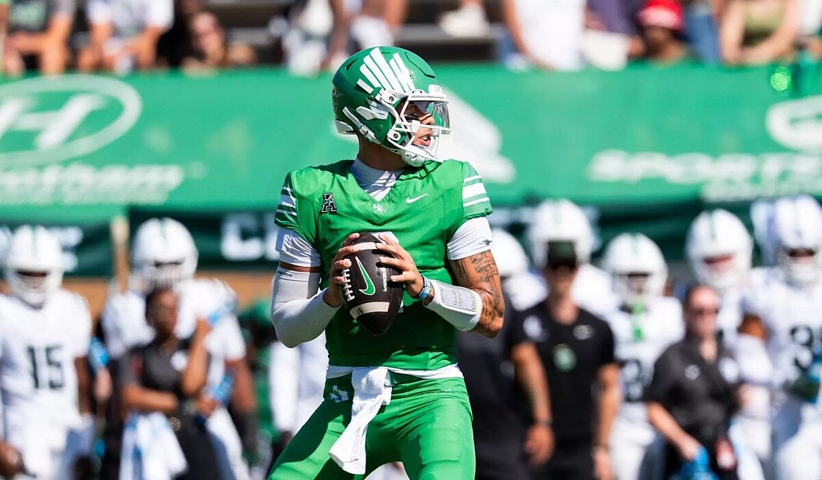 North Texas quarterback Tayven Jackson drops back with the ball in both hands, scanning the field in an all-green uniform.