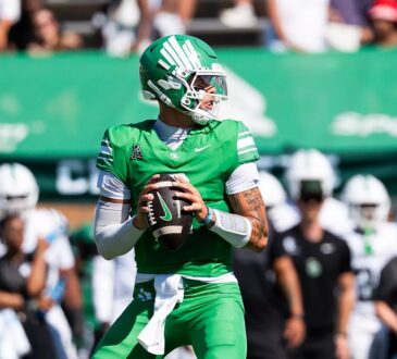 North Texas quarterback Tayven Jackson drops back with the ball in both hands, scanning the field in an all-green uniform.