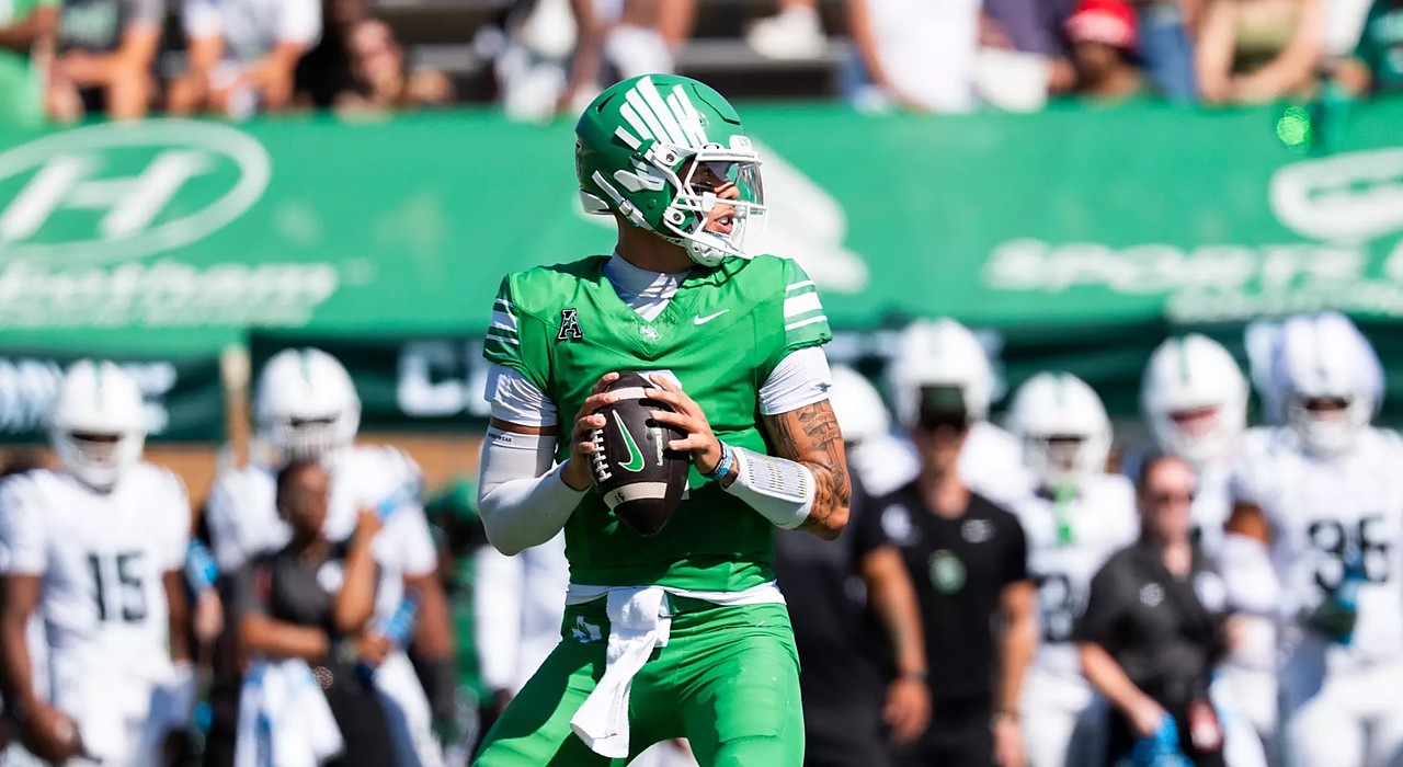 North Texas quarterback Tayven Jackson drops back with the ball in both hands, scanning the field in an all-green uniform.