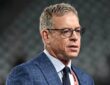 Former Dallas Cowboys quarterback Troy Aikman, in glasses and a blue plaid suit, looks on before the game.