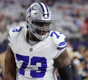 Dallas Cowboys guard Tyler Smith walks through pregame warmups in a white No. 73 jersey and helmet.