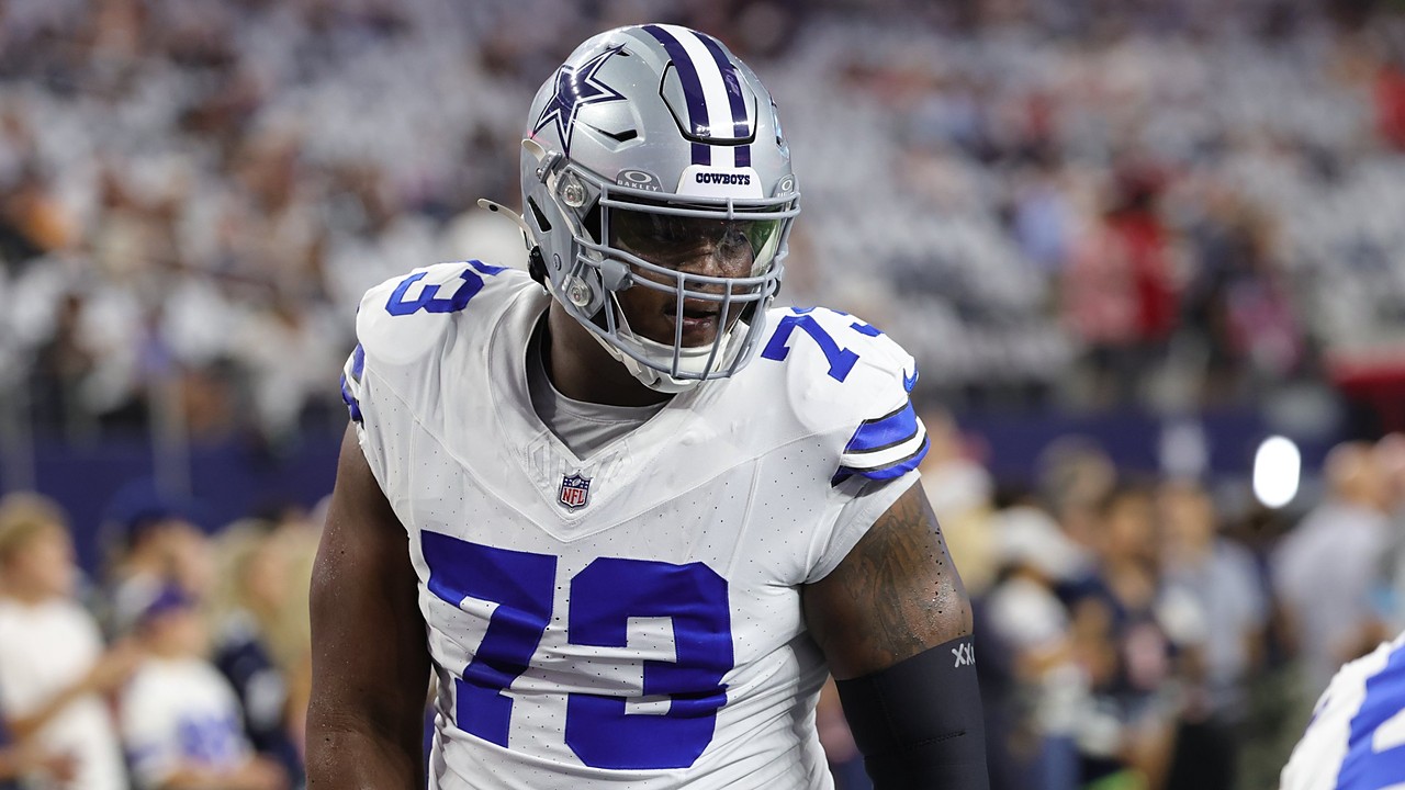 Dallas Cowboys guard Tyler Smith walks through pregame warmups in a white No. 73 jersey and helmet.