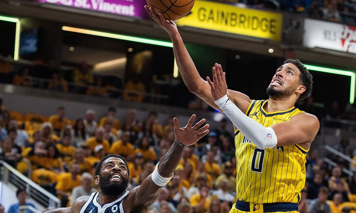 Indiana Pacers guard Tyrese Haliburton lays the ball up as Dallas Mavericks guard Kyrie Irving reaches up from below.