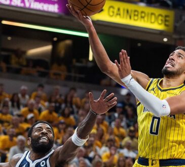 Indiana Pacers guard Tyrese Haliburton lays the ball up as Dallas Mavericks guard Kyrie Irving reaches up from below.